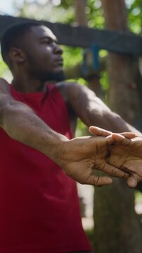 Vertical video of young adult African American man stretching arms and interlocking fingers during outdoor workout. Footage is ideal for fitness apps, wellness campaigns, and sports marketing