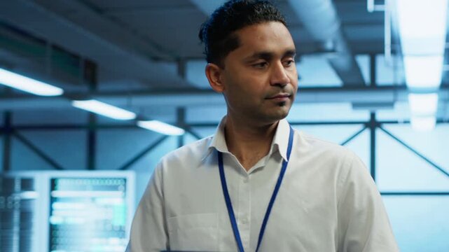 Male programmer checks infrastructure energy use in a modern server farm with a tablet, combining energy efficiency, power use control and database reliability during system reliability work