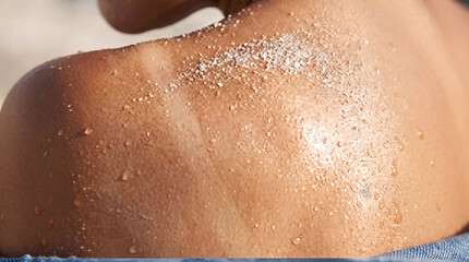 Fototapeta premium Macro view of sun-kissed human skin with sand and salt water residue, shoulder