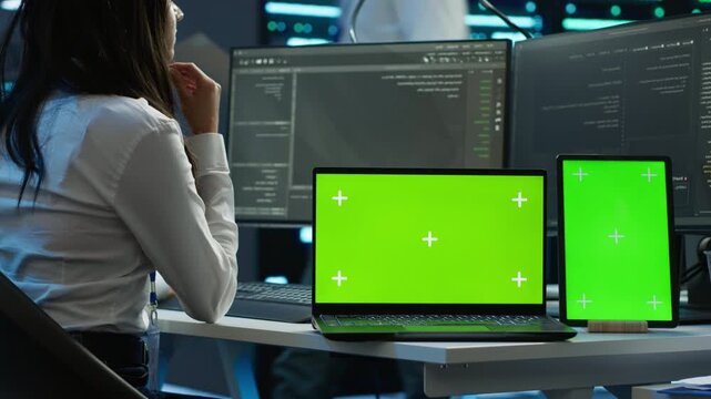 Inside a data center, engineer monitors cybersecurity risks with a chroma key tablet, linking network security, data protection and screen replacement while keeping digital systems reliable