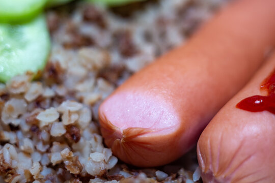 Delicious sausages served with cooked buckwheat and fresh slices for a healthy breakfast or lunch