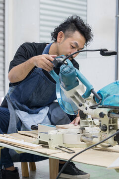 DIY・木工でスライド丸ノコを使って木材加工する男性職人 電動工具による趣味の家具製作の作業風景