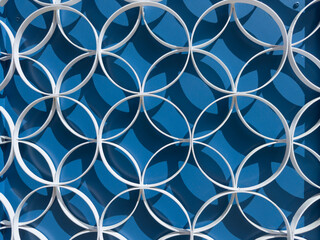 Fototapeta premium White metal circular lattice on vibrant blue surface