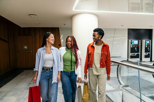 Female friend group walking with shopping bags in mall