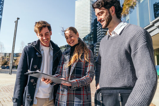 Coworkers review a document outdoors in a modern city