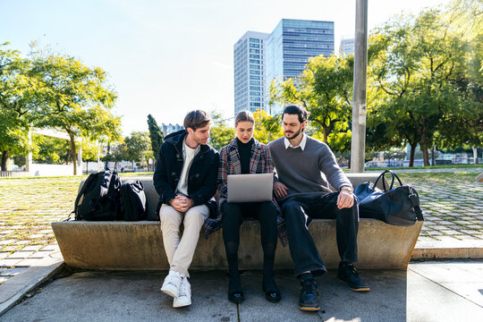 Business coworking team using laptop on city bench