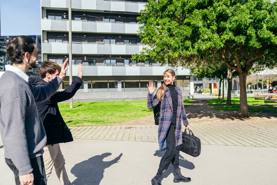 Business colleagues wave goodbye outside modern office