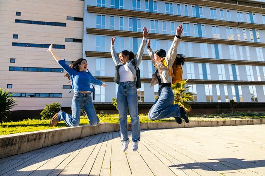 Students jumping with joy outside a modern university campus
