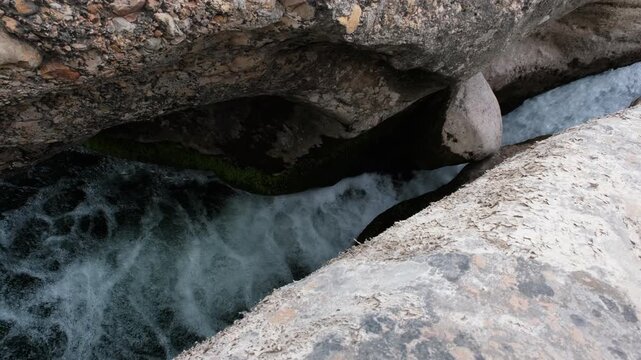 Footage of a stone stuck in a crevice above a waterfall in Charca del Molino (natural limestone pool). Arnes, Tarragona, Spain.