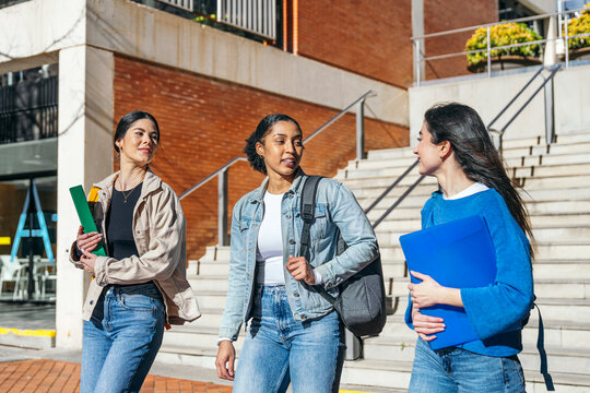 University student walking on campus with folder and backpack