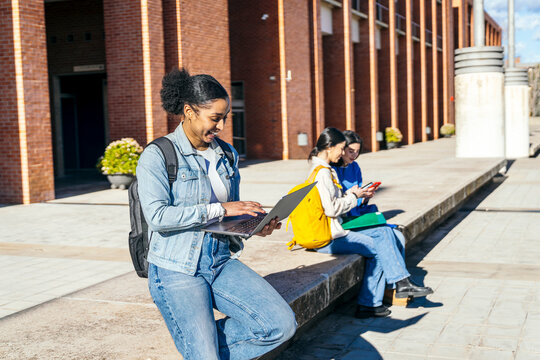 University students studying outdoors on campus with laptop