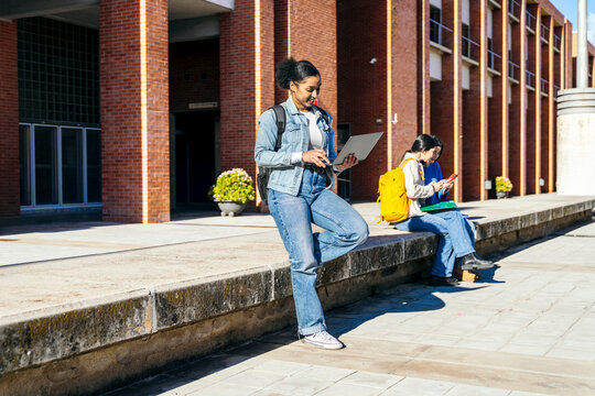 University students studying outdoors on campus with laptop