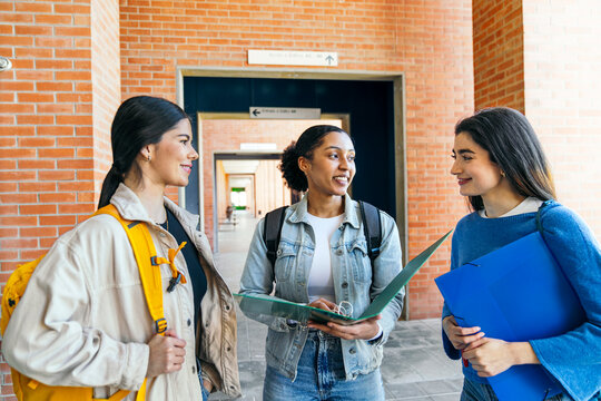 University students discussing notes in campus walkway
