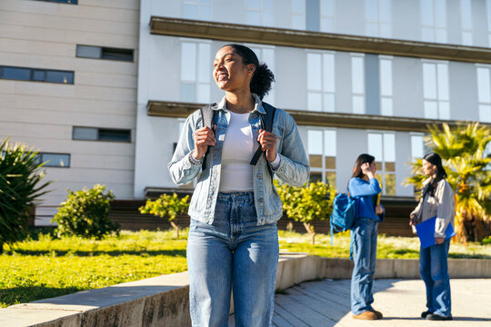University student walking on campus with backpack outdoors
