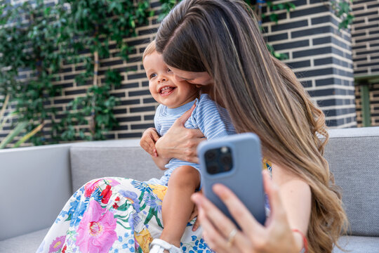Mother taking smartphone selfie with smiling baby son