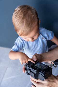 Caucasian boy exploring a digital camera with adult help
