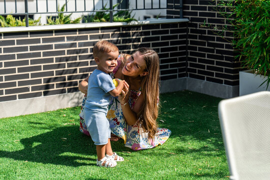 Mother and young son playing on a sunny backyard lawn