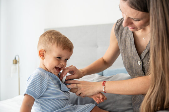 Mother checking son temperature with thermometer at home