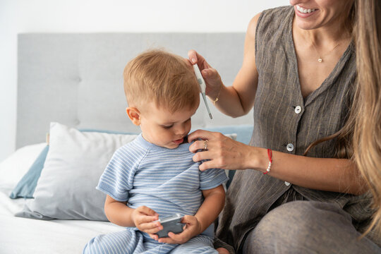 Mother checks son temperature at home with thermometer