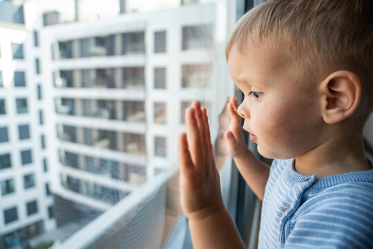 Caucasian boy looking out apartment window in city