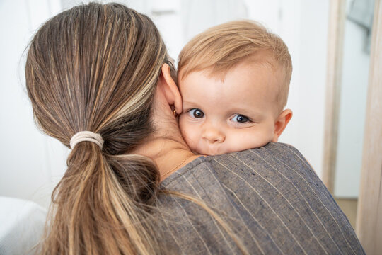 Mother holding baby son over shoulder in cozy home