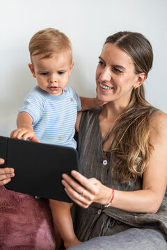 Mother and son using tablet at home on couch together