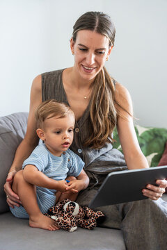 Mother and son using tablet together on a sofa at home