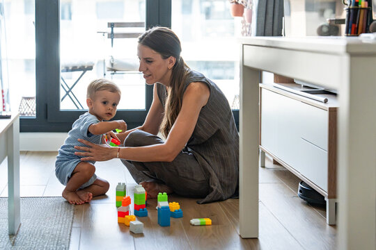 Mother and son playing with colorful toy blocks at home