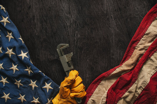 Work glove holding a wrench with the American flag. Symbolic of blue collar workers, USA manufacturing, pride in products Made in United States of America, or for Father's day or US Labor Day.