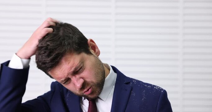 Man in suit scratching his head with dandruff at home