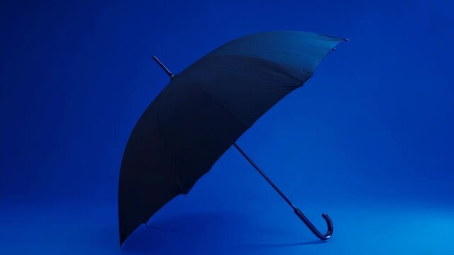 A solitary black umbrella with a metal handle stands out against the backdrop of a dark and rainy evening.