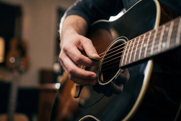 Fototapeta premium Musician hand playing acoustic guitar with green pick