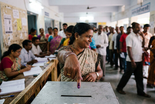 Indian woman showing ink mark on finger after voting at polling station