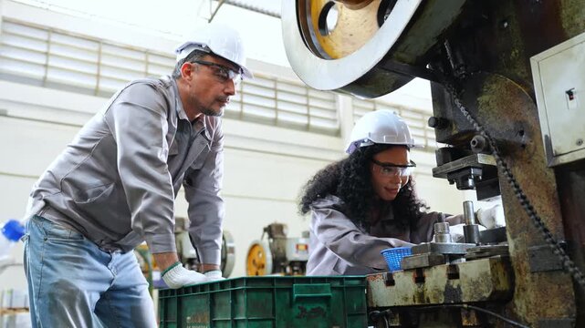 Team of engineers working together in a manufacturing plant concentrating on machinery and the production process