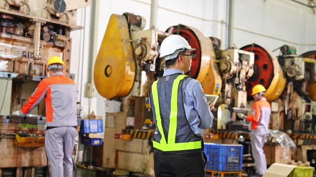 Team of industrial workers wearing safety equipment working together in a manufacturing environment