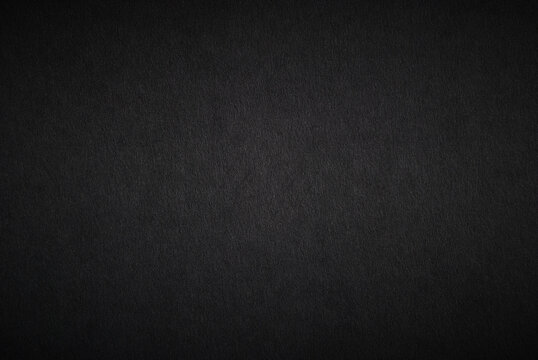 Black paper sheet texture with light vignette background	
