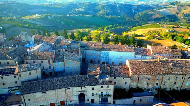 Wonderful aerial stationary shot from Monte Rinaldo with a flock of birds flying in graceful arching fashion through the atmosphere, while the town's centre and surrounding Marche hillscapes lie below