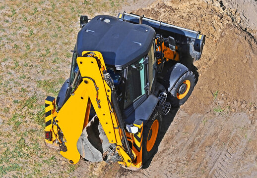Hydraulic backhoe loader moving soil