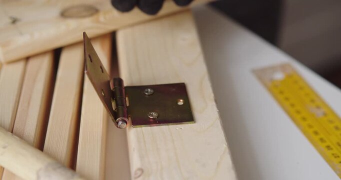 Close-up of a carpenter installing a hinge onto a wooden door.