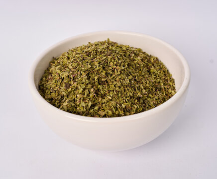 Ceramic bowl filled with dried oregano leaves isolated on white background
