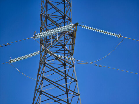 High-voltage transmission tower with glass insulators against a clear blue sky