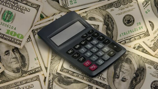 Black Digital Calculator Placed on Stacked US Dollar Bills Background