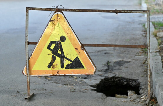 Road work sign near a hole in the asphalt