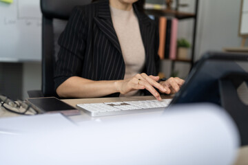 Fototapeta premium Woman types on keyboard at desk. Focused, calm, professional. Office environment, natural lighting. Perfect for business, productivity, remote work. Minimalist background, clean composition