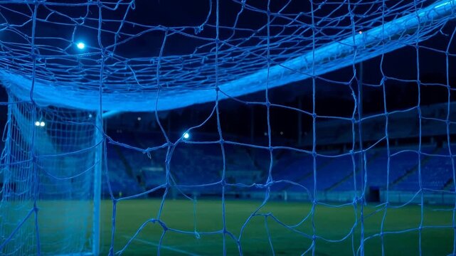 Nighttime view from inside a soccer goal net at an empty stadium