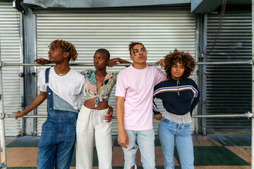 Obraz premium Four stylish individuals posing casually in front of a metal backdrop.