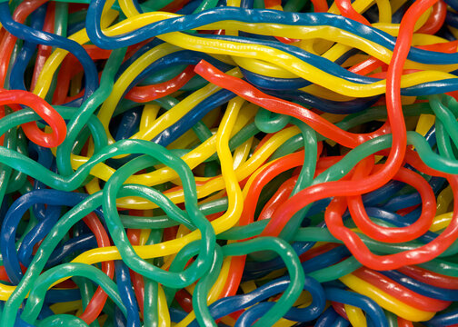 Close up of colorful strings of licorice in multiple flavors. Yellow, green, blue and red tangled up together in a pile.