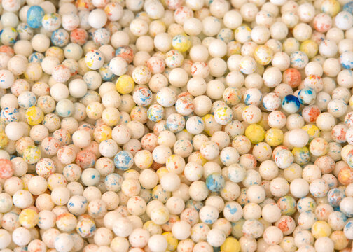 Close up view of many hard round small gum ball type candy. Speckled with color.