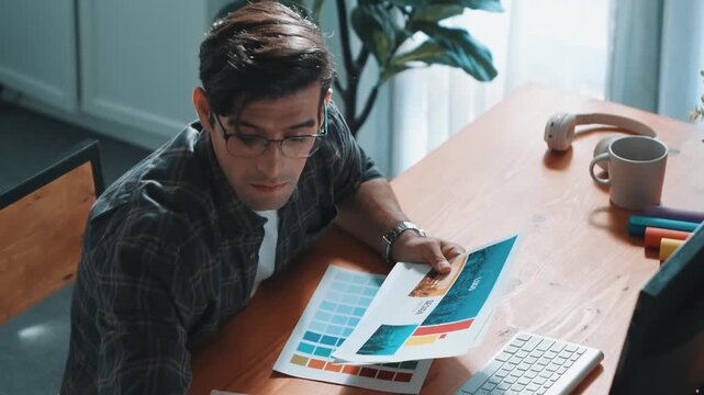 Professional designer writing and designing logo graphic at meeting. Closeup of business man working on colored palettes and writing idea on sticky notes on table with equipment and paper. Symposium.