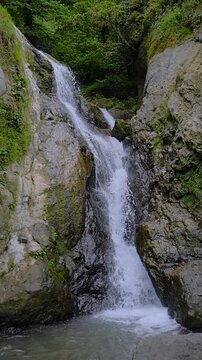 Vertical video: Andrew the Apostle waterfall in the mountain - river or stream of water is flowing and falling down - slow motion. Nature, landscape and environment concept